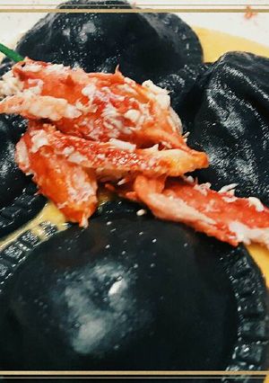 Una foto de Sorrentinos de centolla & salsa de calabaza con tinta de calamar