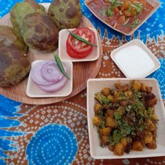 A picture of Palak puri, tariwale aloo, kasuri methi sukha aloo, salad & curd.