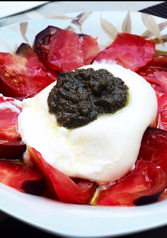 Una foto de Ensalada de burrata, tomate azul y salsa de trufa