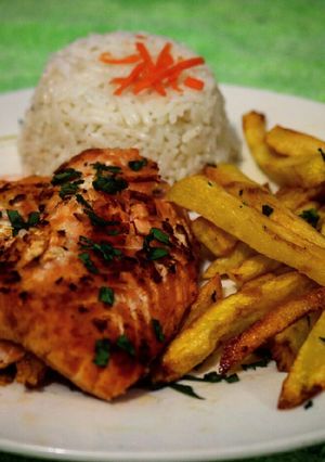 Una foto de Salmón a la mantequilla acompañado de papas fritas y arroz