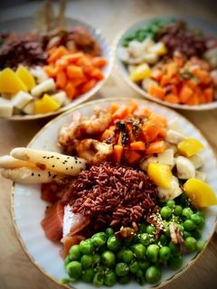 Una foto de Poke de arroz castaño con salmón marinado y langostinos al ajillo