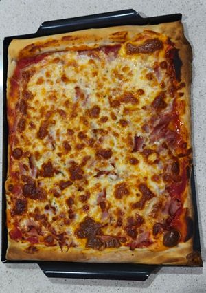 Una foto de Pizza prosciutto con bordes rellenos de cheddar (masa en Thermomix)