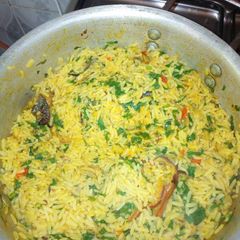 A picture of Jollof rice with dry fish and green leaf.
