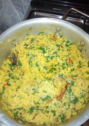A picture of Jollof rice with dry fish and green leaf.