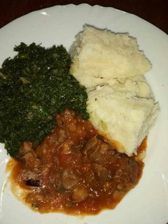 A picture of Wet fried beef, kales and ugali.