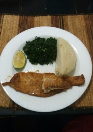 A picture of Grilled fish fillets with steamed kales and ugali.