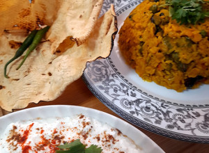 A picture of Kathyawadi masala vegetable khichadi with masala curd, papad and 🌶.