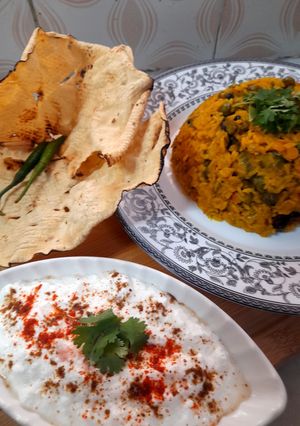 A picture of Kathyawadi masala vegetable khichadi with masala curd, papad and 🌶.