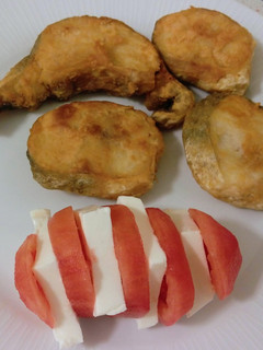 Una foto de Merluza frita y pincho de tomate con queso fresco