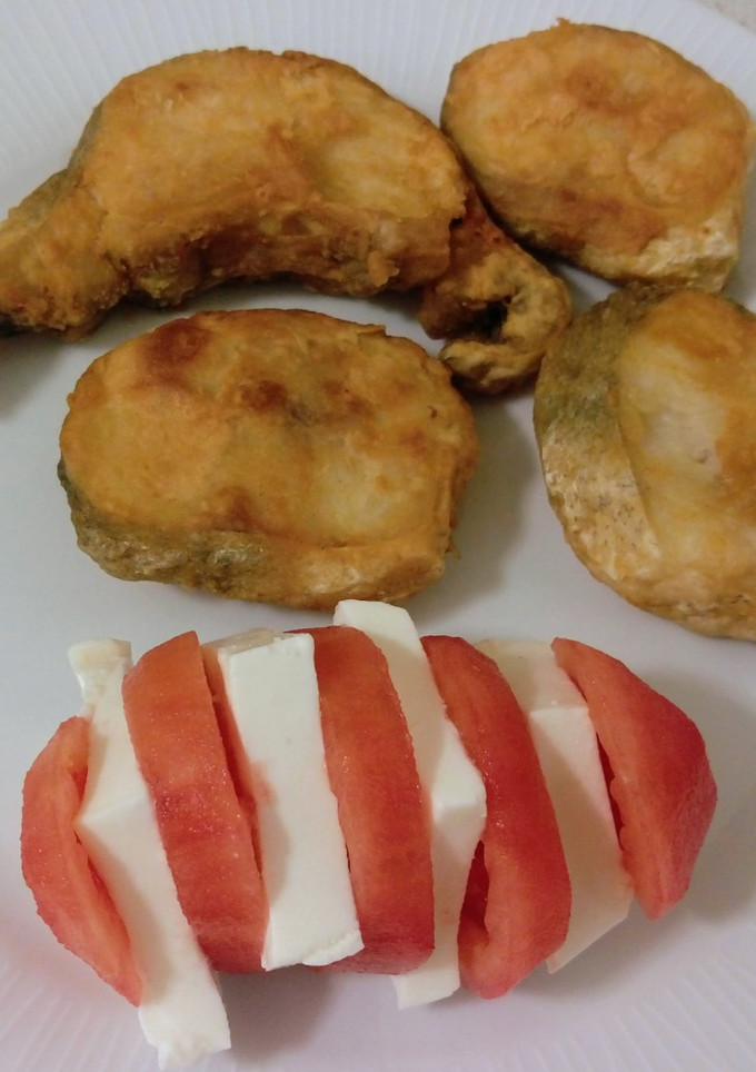 Una foto de Merluza frita y pincho de tomate con queso fresco