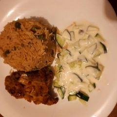 A picture of Rice served with coated chicken and sauce.
