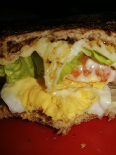 Una foto de Sándwich de huevo, queso, lechuga y tomate