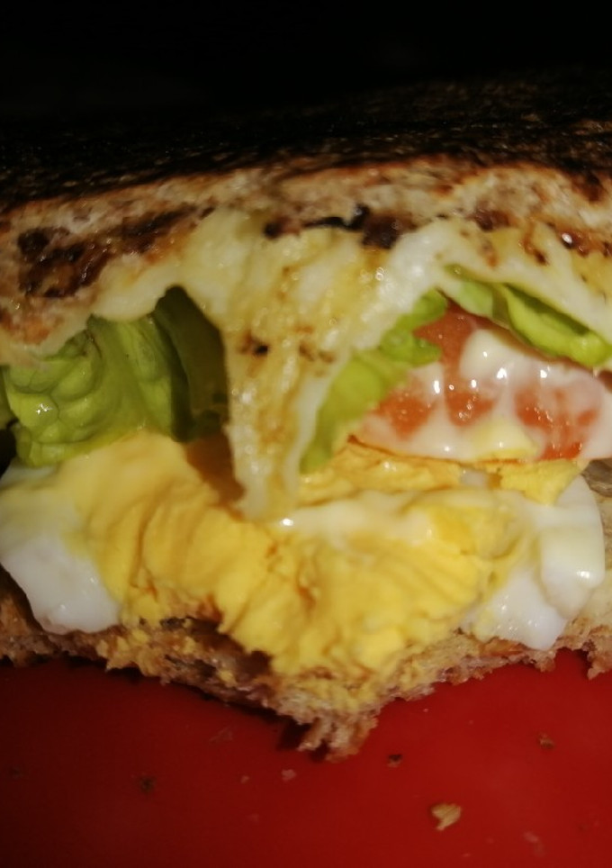 Una foto de Sándwich de huevo, queso, lechuga y tomate