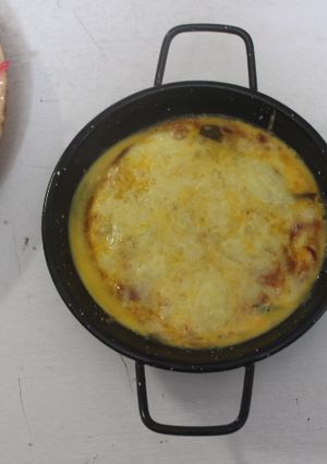 Una foto de Sartenes individuales con verduras cocidas y huevos rotos