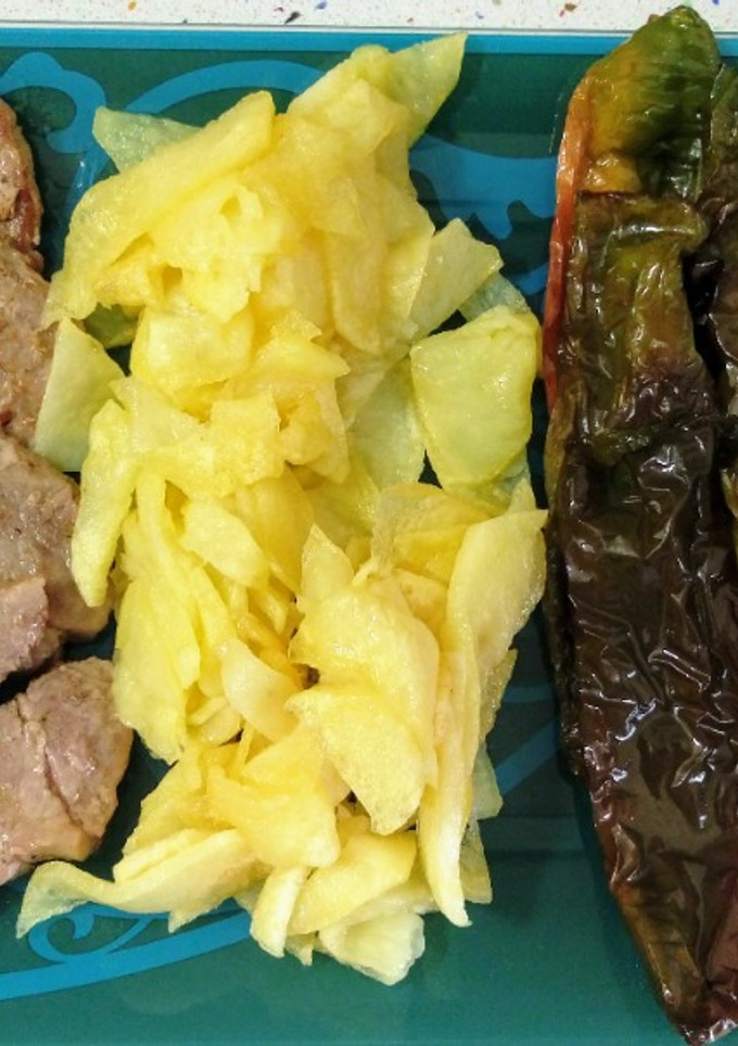 Una foto de Chuletas de cerdo y tomatitos asados con patatas y pimientos fritos