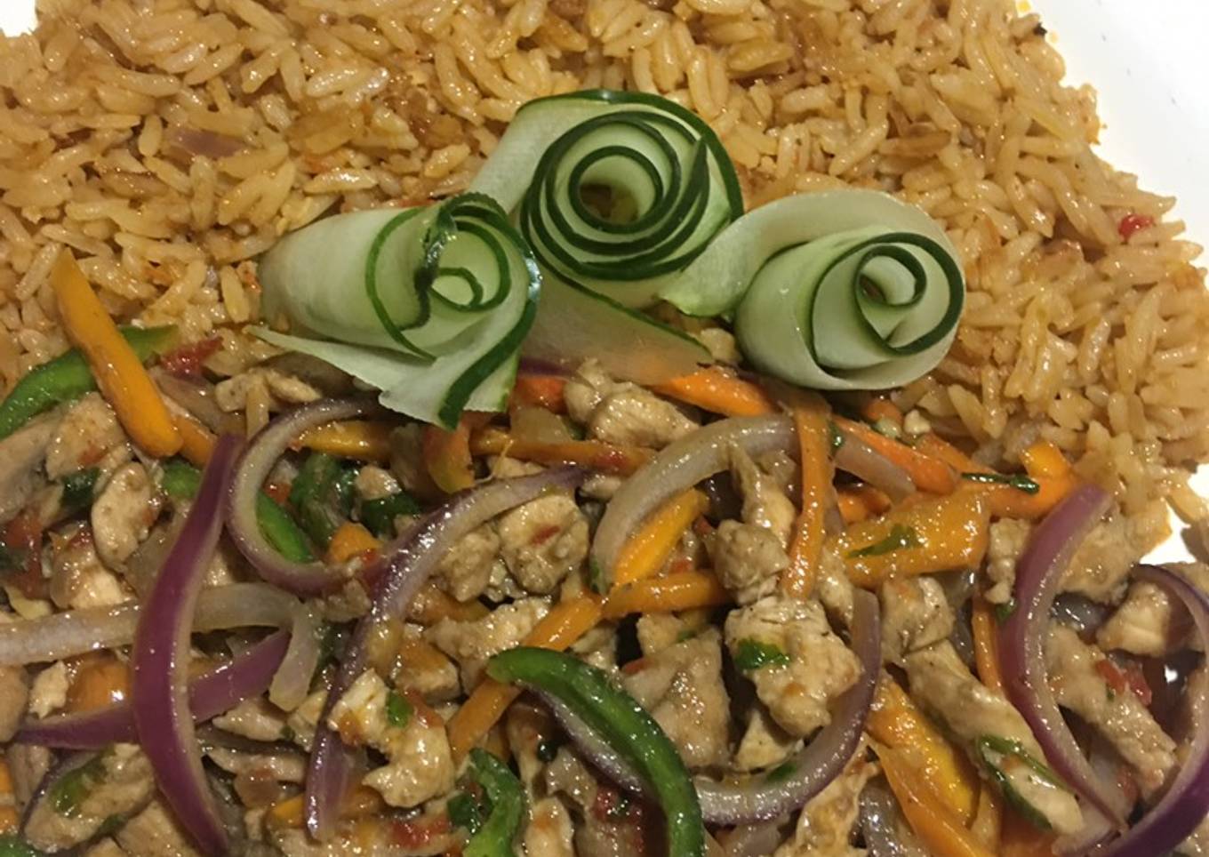 Stir fried chicken with veggies served with jollof rice