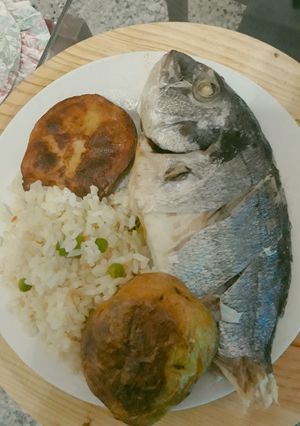 Una foto de Dorada al horno empapelado acompañado con papas y arroz