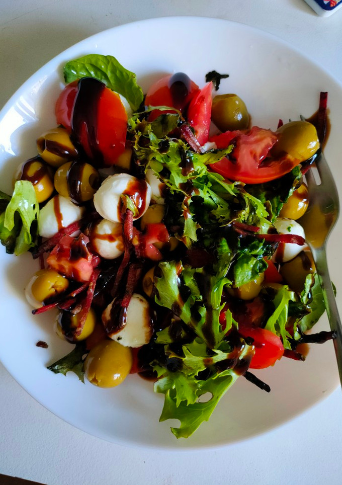 Una foto de Ensalada de tomate con rúcula, aceitunas y mozzarella