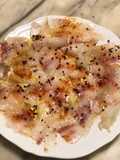 Carpaccio di branzino marinato con limone sriracha e pepe rosa