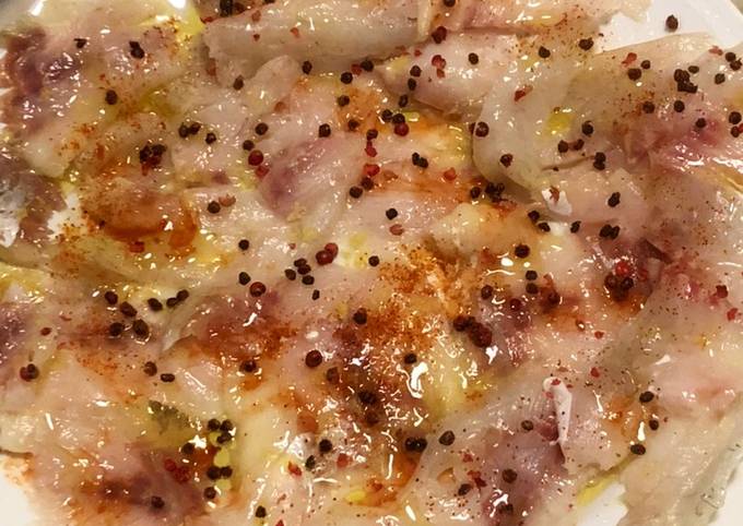 Carpaccio di branzino marinato con limone sriracha e pepe rosa