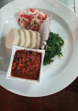 A picture of Ugali served with beans stew and vegetables.