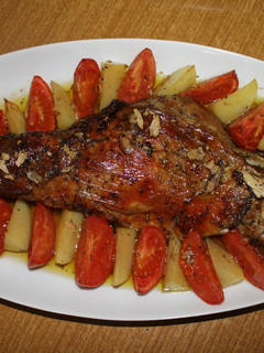 Una foto de Paletilla de cordero al horno con hierbas aromáticas y guarnición de gajos de patata y tomate asados
