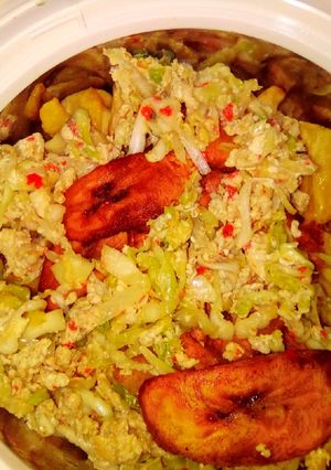 A picture of Egg and cabbage sauce with chips and plantain.