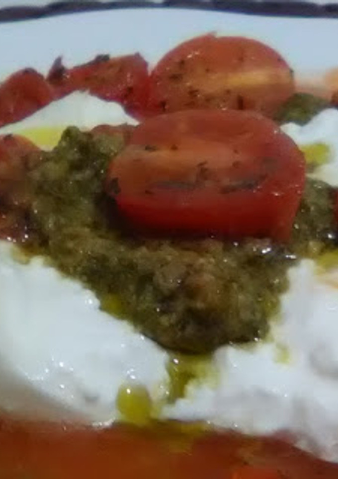 Una foto de Ensalada de burrata sobre tomate rallado con tomatitos salteados y salsa pesto