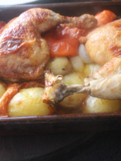 Una foto de Pollo al horno con patatas, tomate, cebolletas y ajo