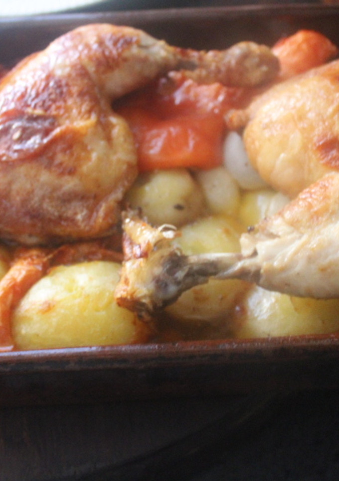 Una foto de Pollo al horno con patatas, tomate, cebolletas y ajo
