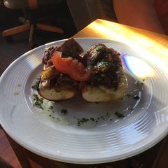 A picture of Open Faced Steak Sandwiches on Garlic Bread with Aged Provolone, Caramelized Onions, and Parsley Oil.