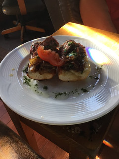 A picture of Open Faced Steak Sandwiches on Garlic Bread with Aged Provolone, Caramelized Onions, and Parsley Oil.