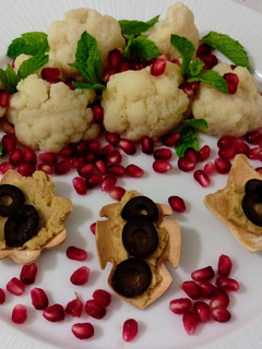 Una foto de Ensalada de coliflor con granada y menta y flores con hummus y aceitunas