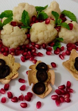 Foto principal de Ensalada de coliflor con granada y menta y flores con hummus y aceitunas