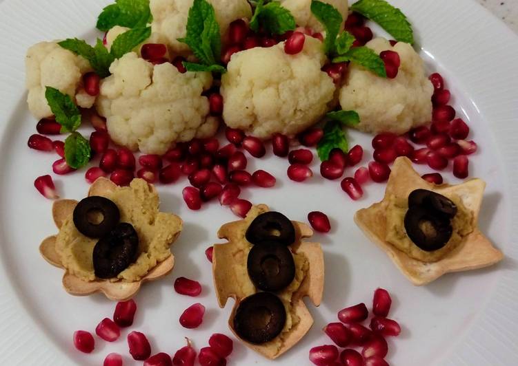 Ensalada de coliflor con granada y menta y flores con hummus y aceitunas