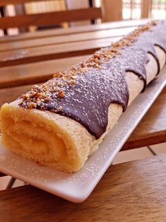Una foto de Bracito relleno de crema de limón y chocolate blanco con cobertura de chocolate y crocanti