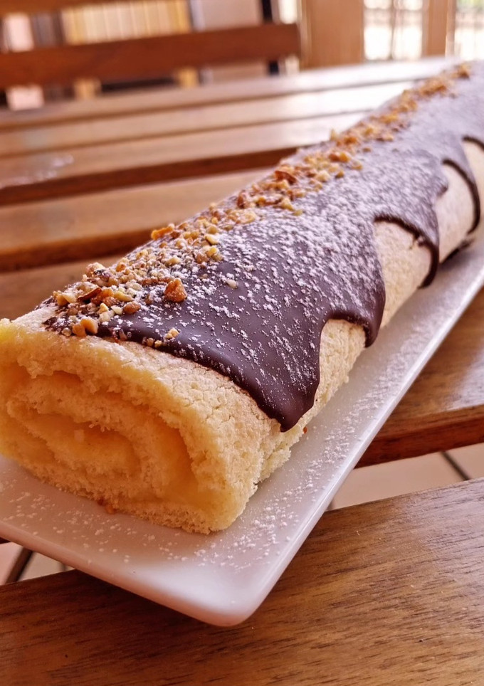 Una foto de Bracito relleno de crema de limón y chocolate blanco con cobertura de chocolate y crocanti