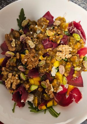 Una foto de Ensalada de rúcula, cecina, mango y rulo de cabra con vinagreta de mostaza y miel