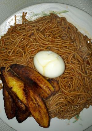 A picture of Spaghetti with fried plantain and egg.