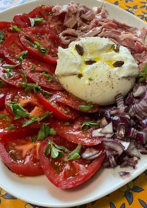 Une photo de Salade de tomates à l'oignon rouge, jambon blanc, basilic et burrata