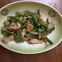 A picture of Fried garlic shoots and pork seasoned with homemade garlic soy sauce.