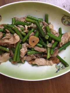 A picture of Fried garlic shoots and pork seasoned with homemade garlic soy sauce.