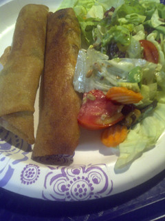 A picture of Spring roll hotdogs with salad.