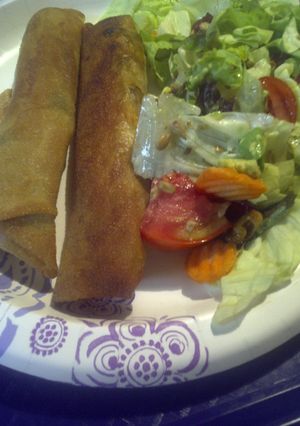 A picture of Spring roll hotdogs with salad.