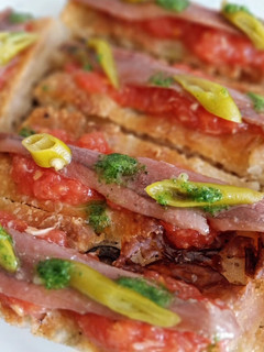 Una foto de Pincho focaccia de anchoa, tomate y ajo escalivado con piparras