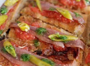 Una foto de Pincho focaccia de anchoa, tomate y ajo escalivado con piparras