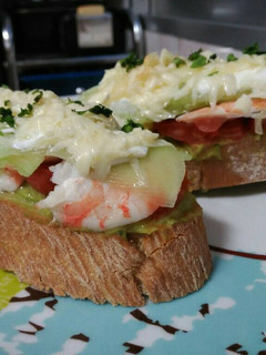 Una foto de Tosta de guacamole, pepino y langostinos