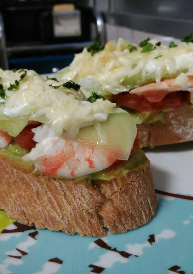 Una foto de Tosta de guacamole, pepino y langostinos