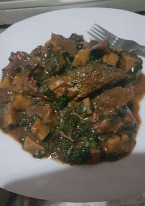 A picture of Platain porridge with diced meat, ugu leaves & oven grilled fish.
