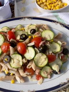 Foto di Pasta fredda integrale, con tonno mais olive nere, pomodorini, zucchina a fette sottili e mandorle
